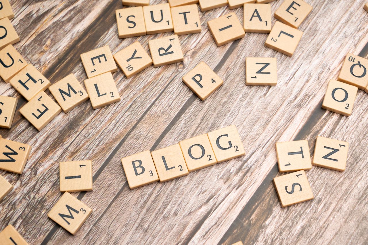 Scattered wooden letter tiles spelling Blog on a rustic wood background.
